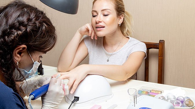 front view young female getting her nails fixed by manicurist inside room beauty manicure nails hand self care lady