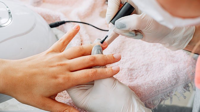 woman receiving manicure from woman gloves mask beauty salon daytime 1